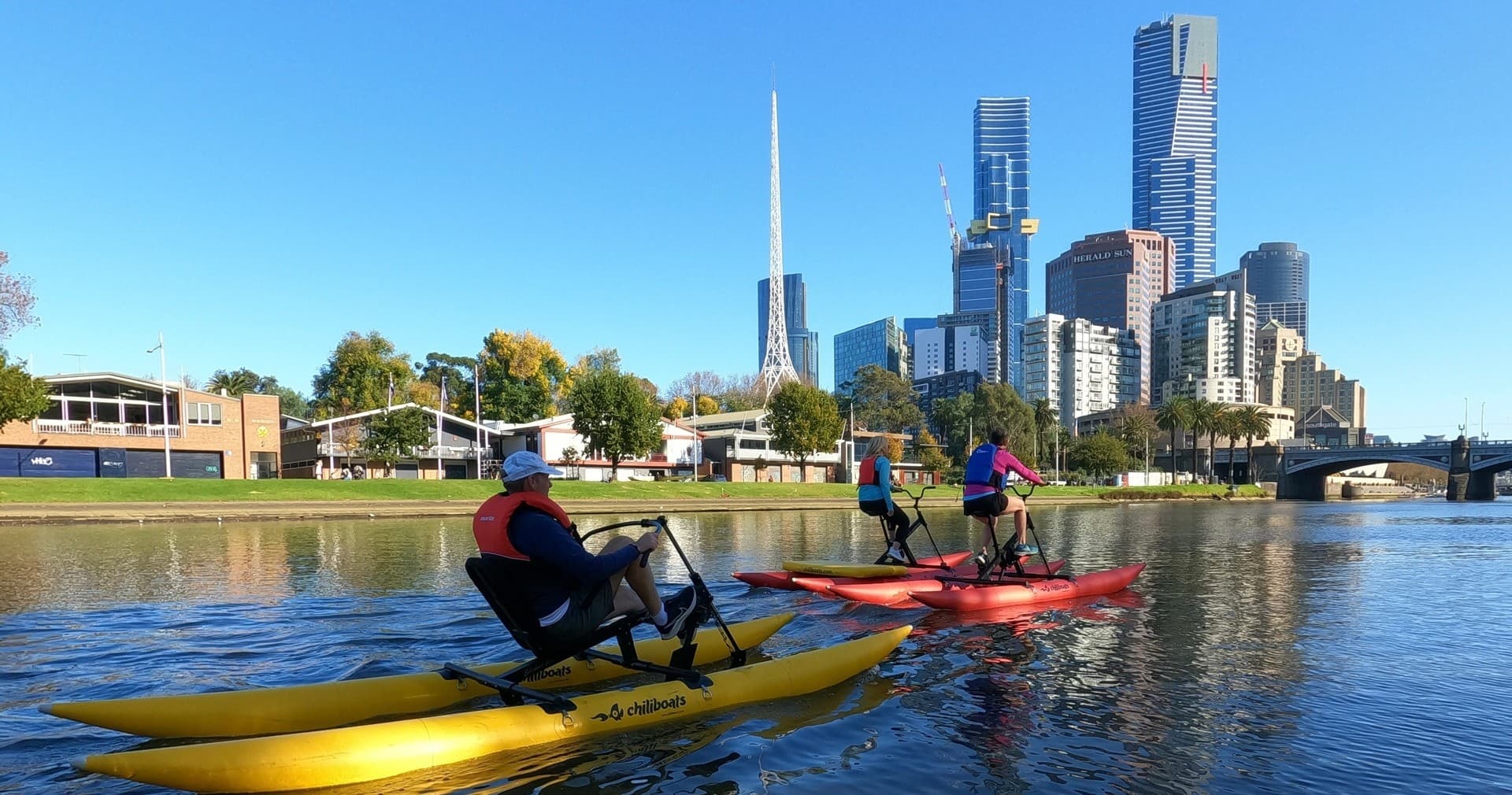 Paddlers on waterbikes with city skyline backdrop on river