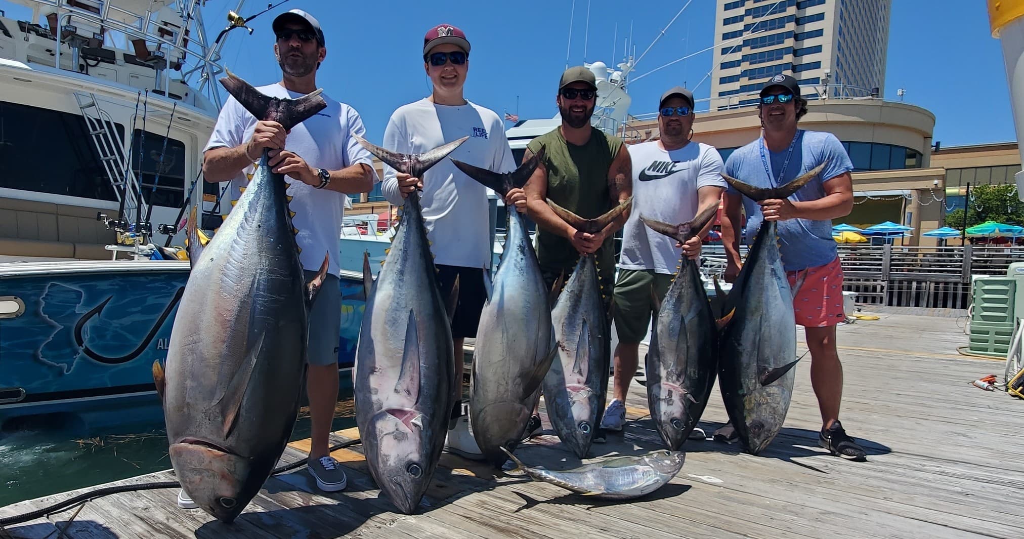 Charter anglers with trophy tuna at marina dock after trip