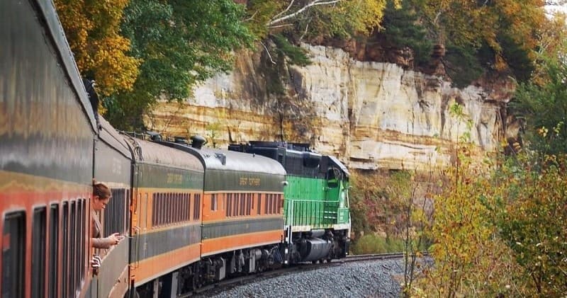 Scenic vintage train rounding rocky cliff through fall forest