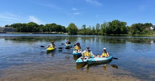 Kayak trip on peaceful lake with paddlers near shore