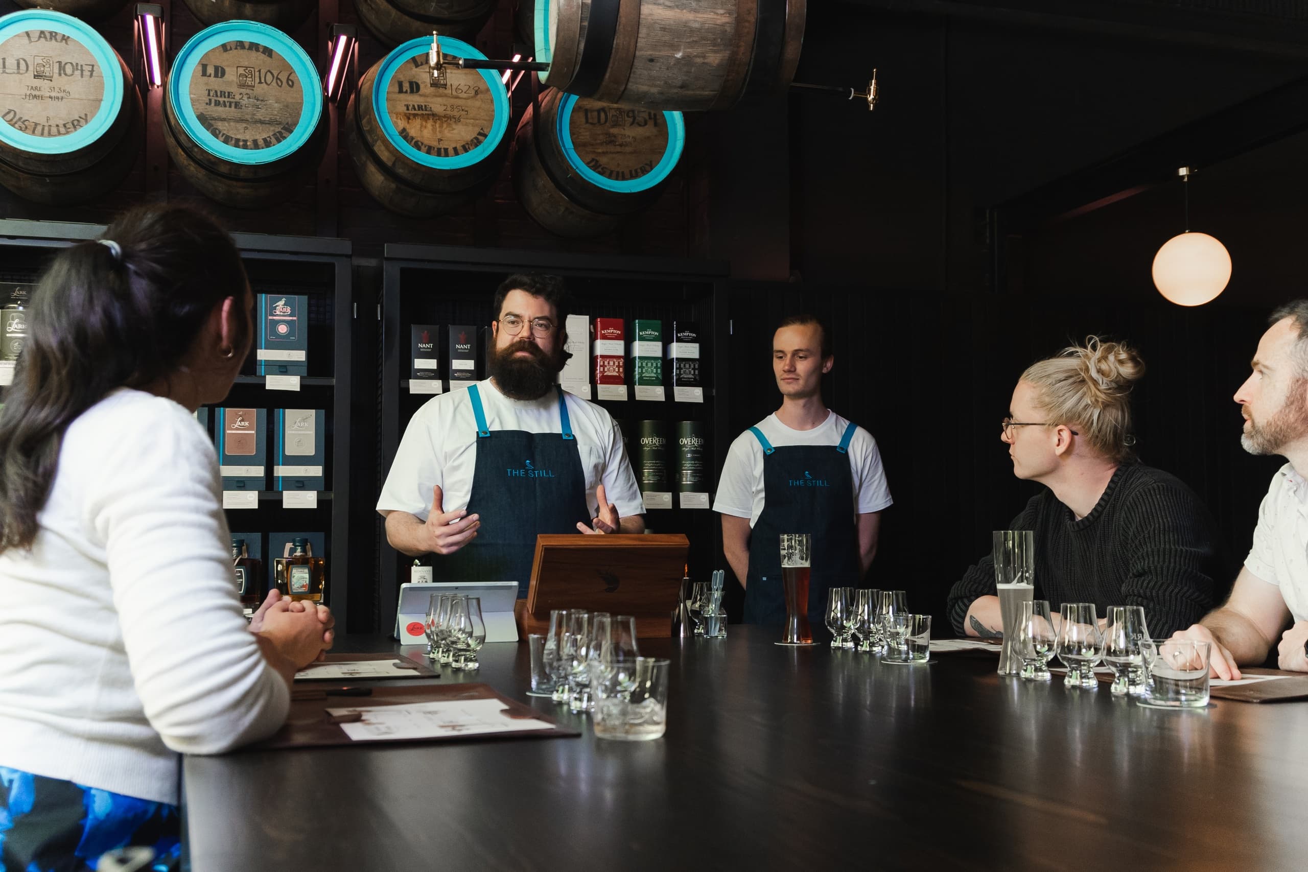Guided whiskey tasting with barrels in background at distillery