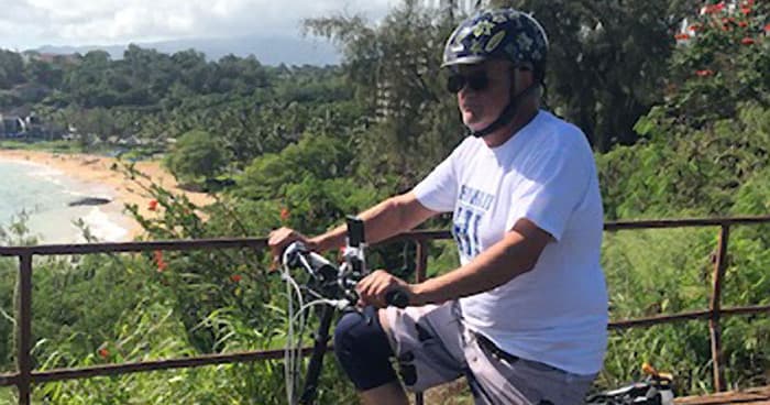 Solo e-bike rider overlooking lush Kauai coast and beach