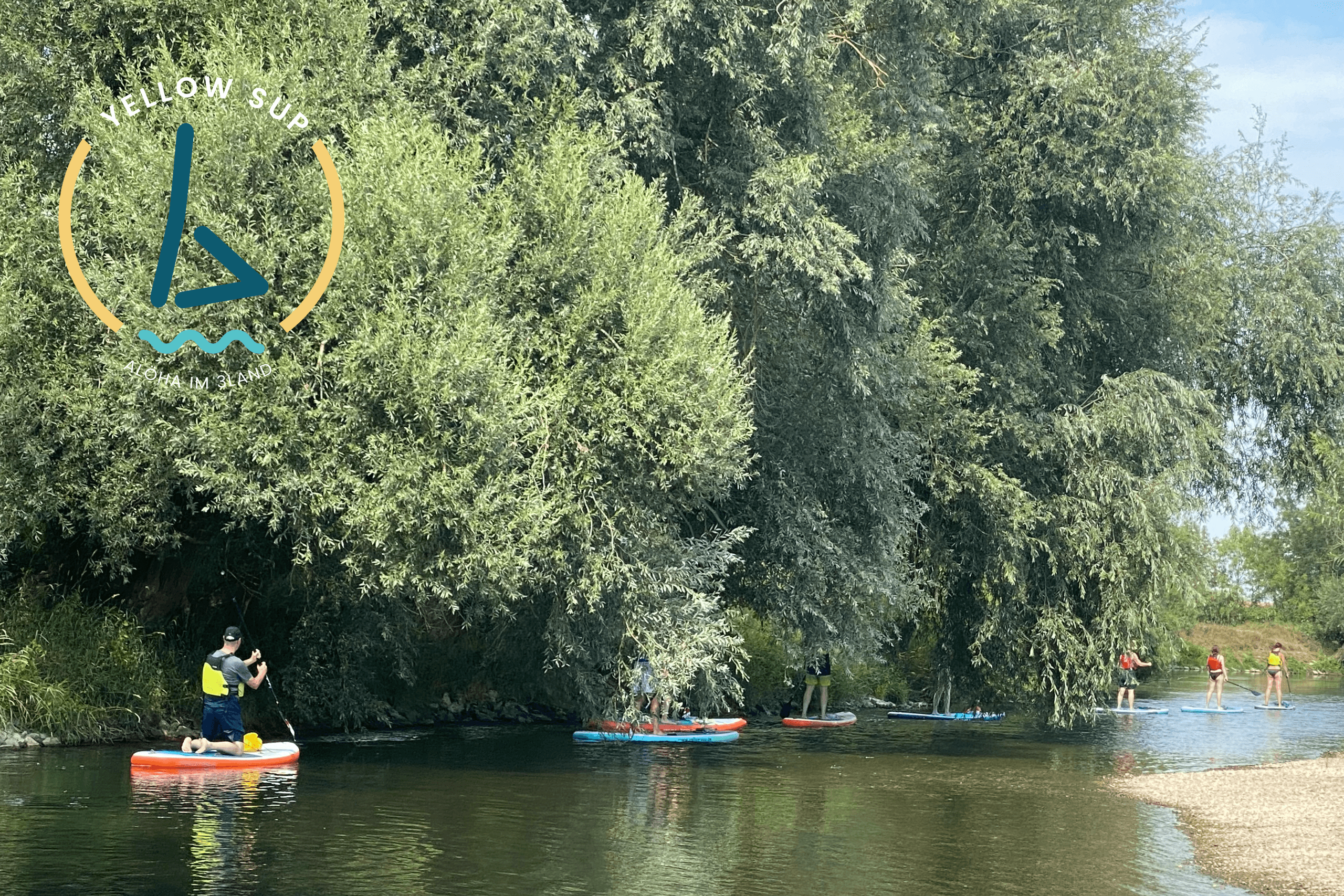 Paddleboarders navigating shaded tree-lined river bend on summer day