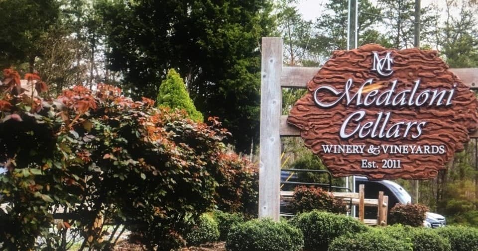 Winery entrance sign among vineyard landscaping and trees