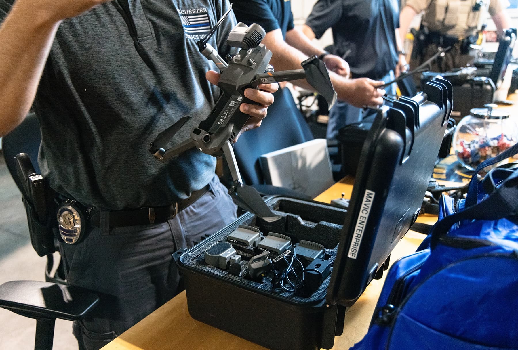 Officer inspecting drone and gear at equipment table indoors