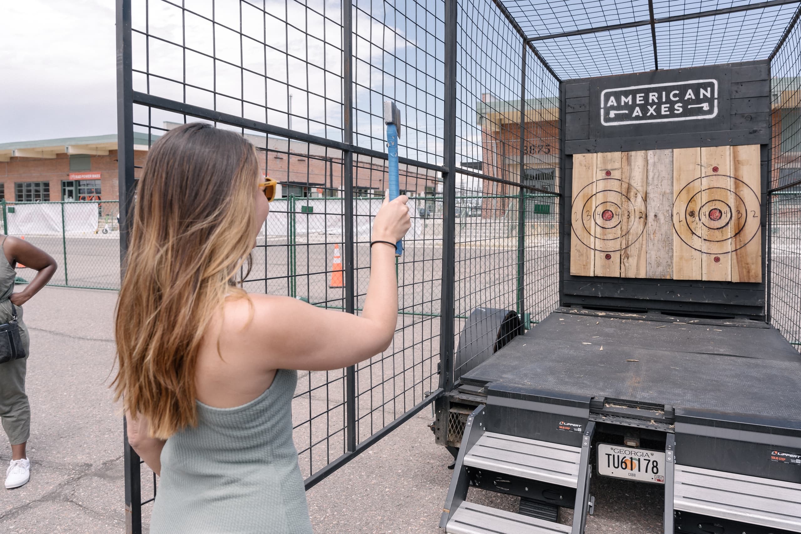 Woman throwing axe at outdoor target range at American Axes trailer
