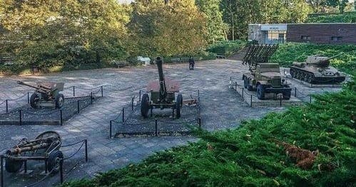 Outdoor artillery memorial display in wooded park setting