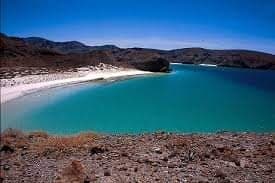 Turquoise coastal bay with sandy beach and desert cliffs