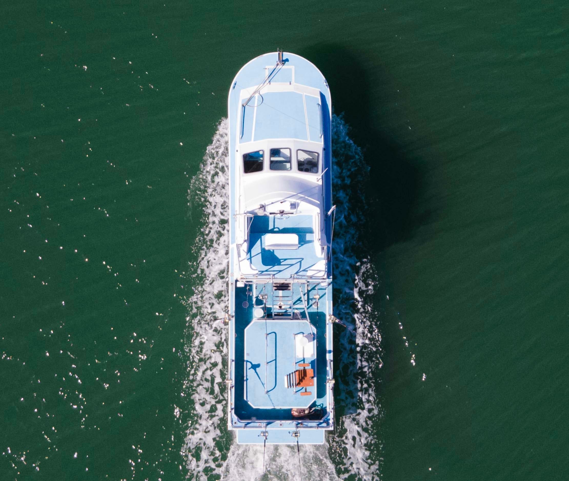 Aerial view of fishing vessel cutting through deep green ocean