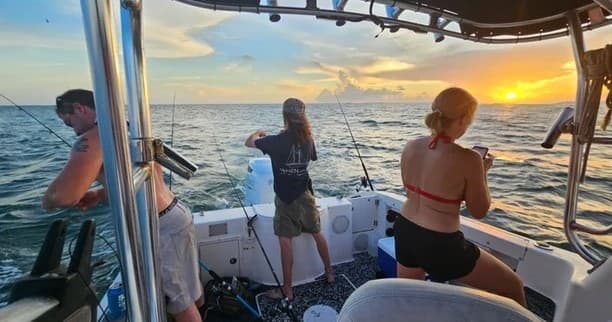 Group deep-sea fishing aboard charter boat at sunset