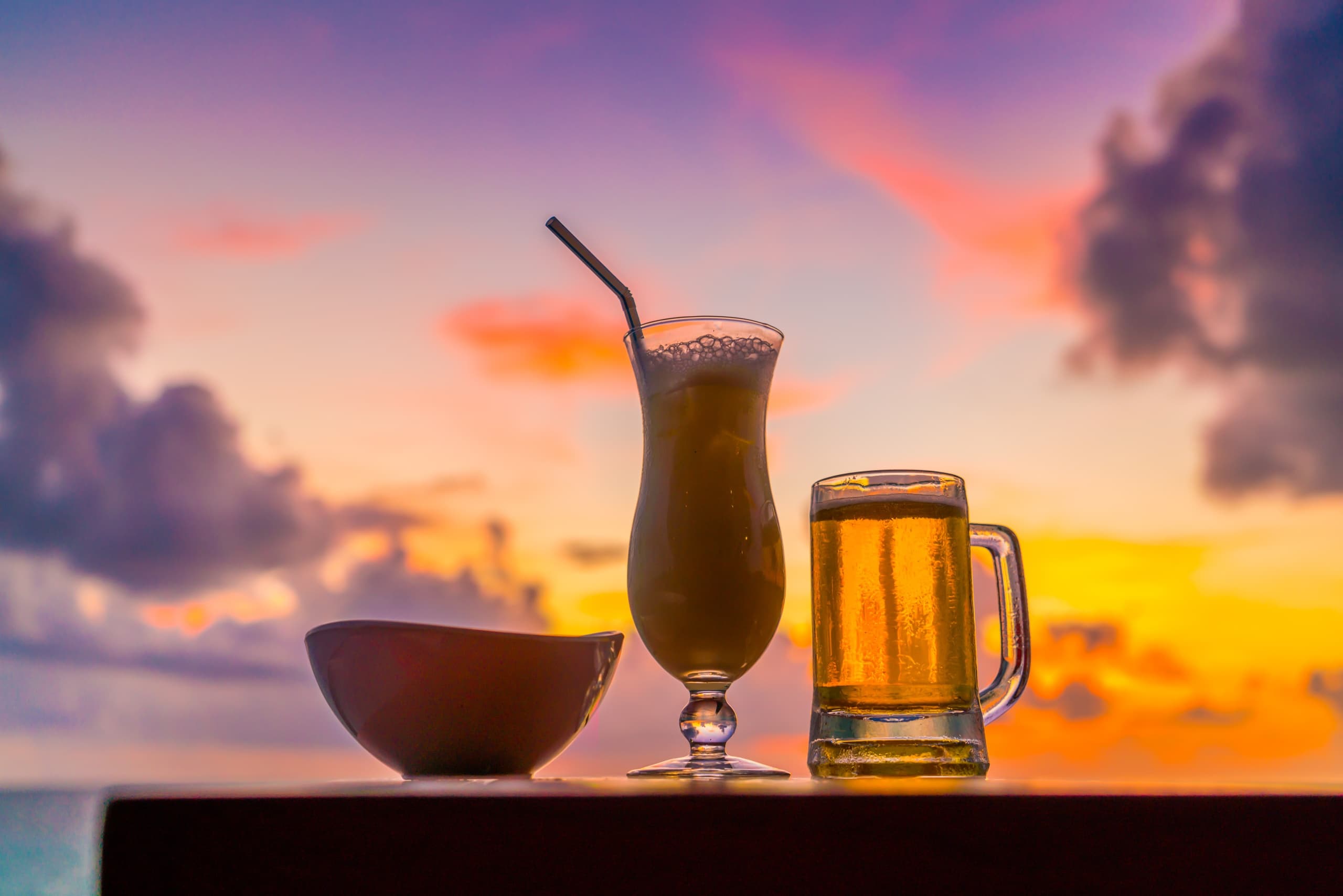 Tropical cocktails and beer on seaside table at sunset view