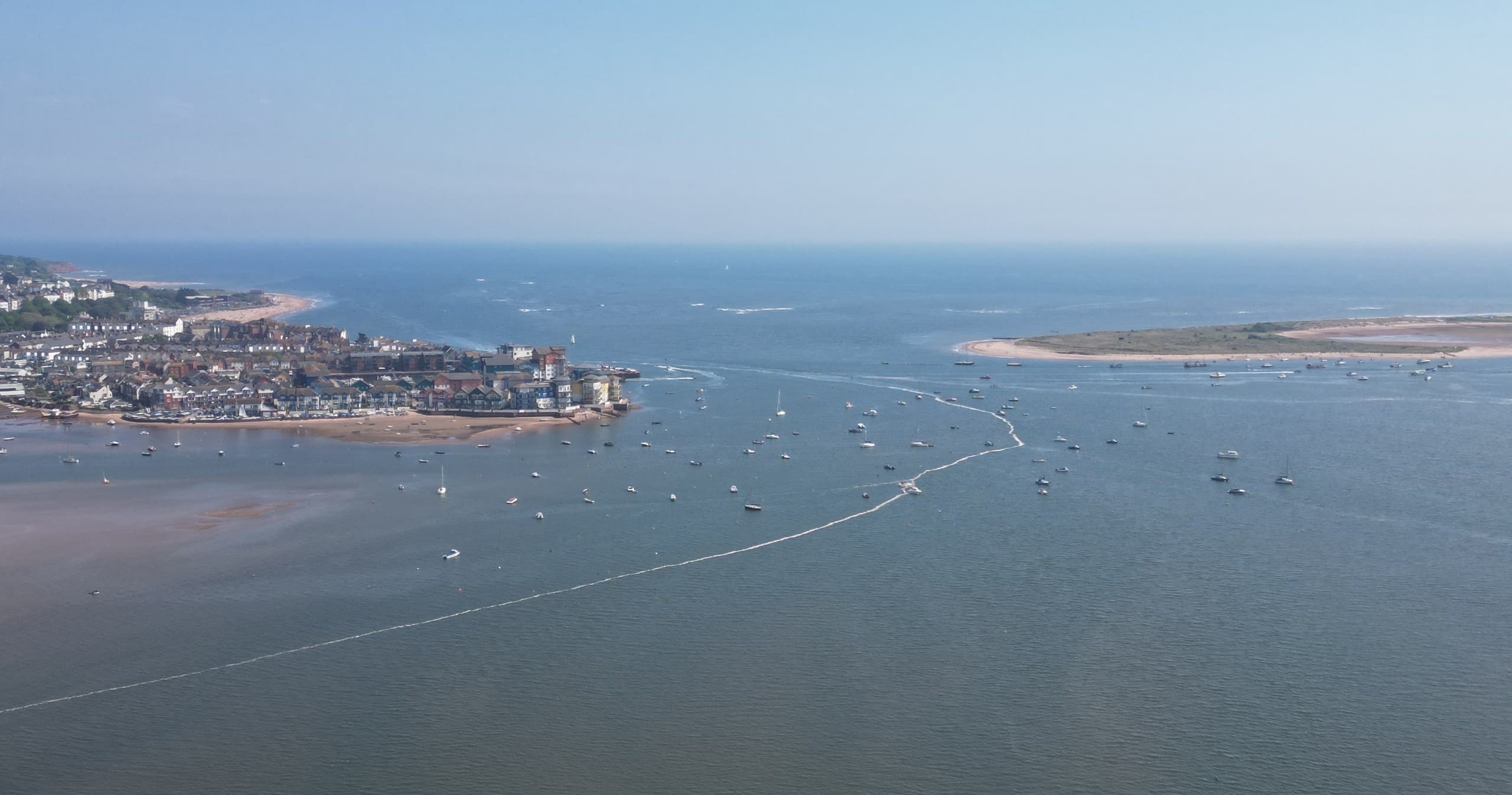 Aerial view of busy coastal estuary with boats and shoreline town