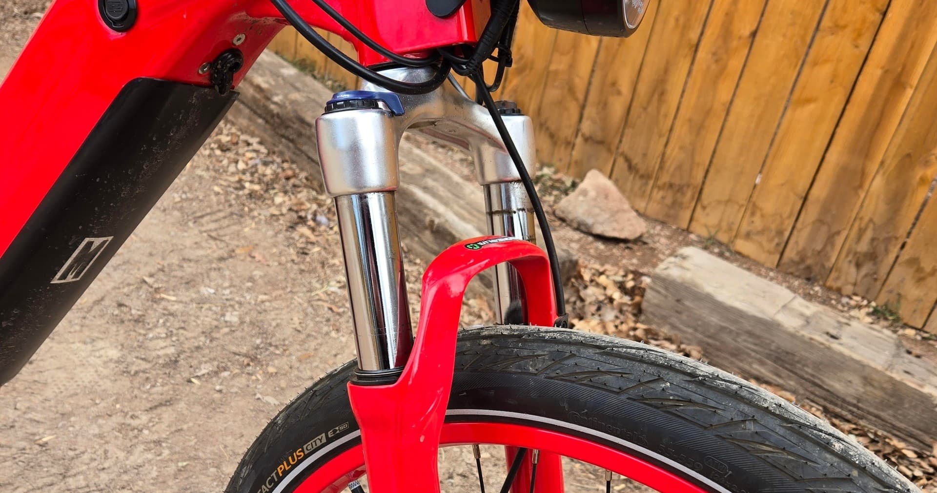 Close-up of red e-bike front suspension and tire on trail