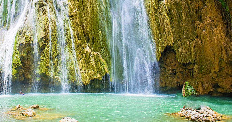 Tropical waterfall cascading into emerald pool in lush jungle