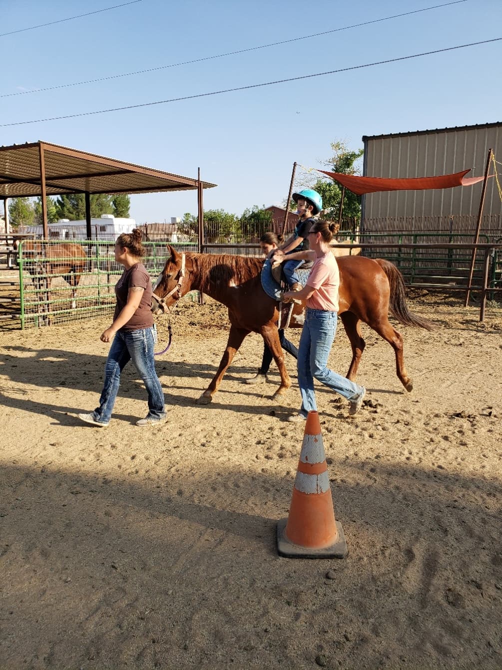 Child guided pony ride in dusty corral with instructor walking