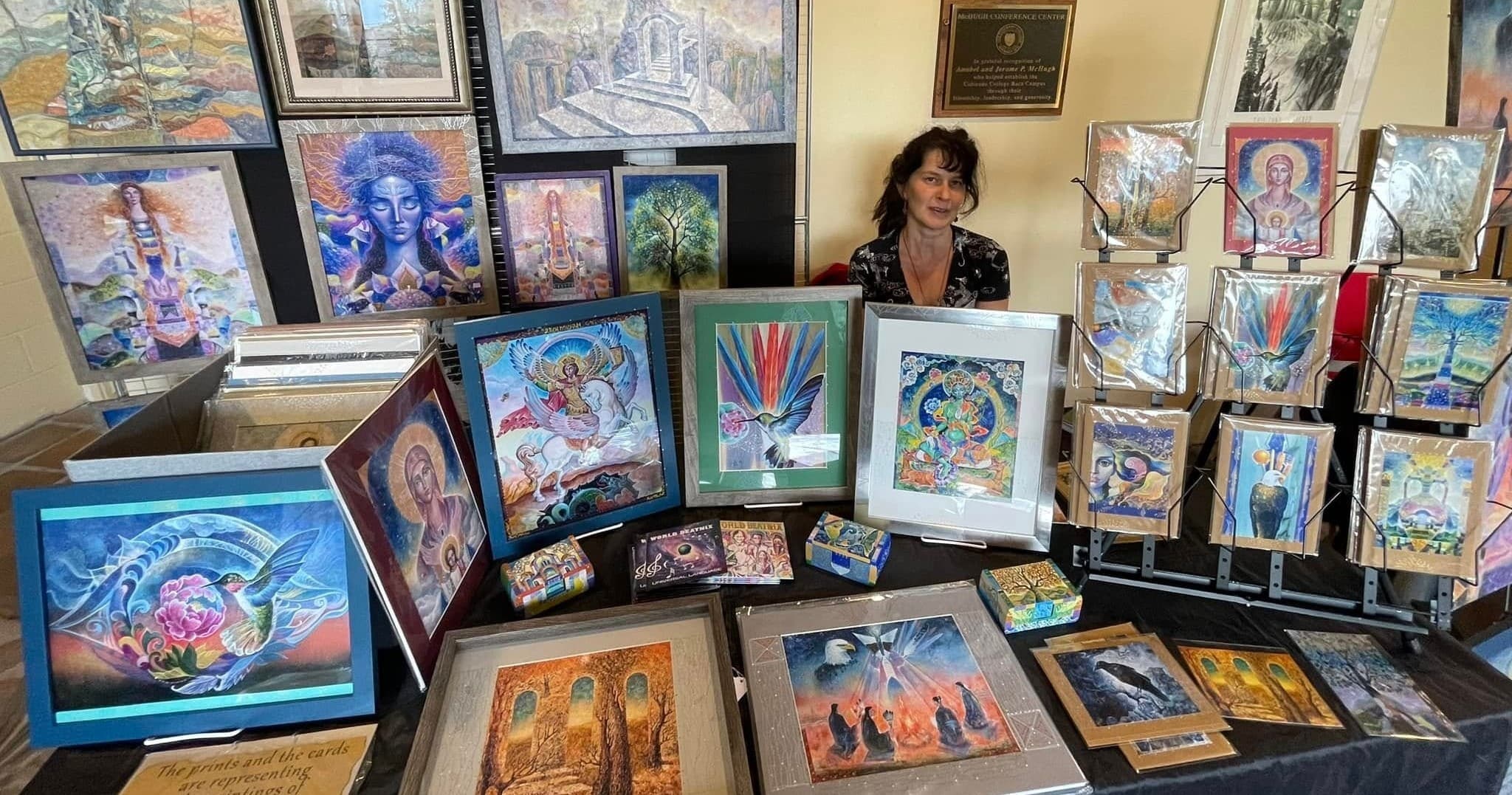 Artist displaying colorful spiritual paintings at indoor gallery booth