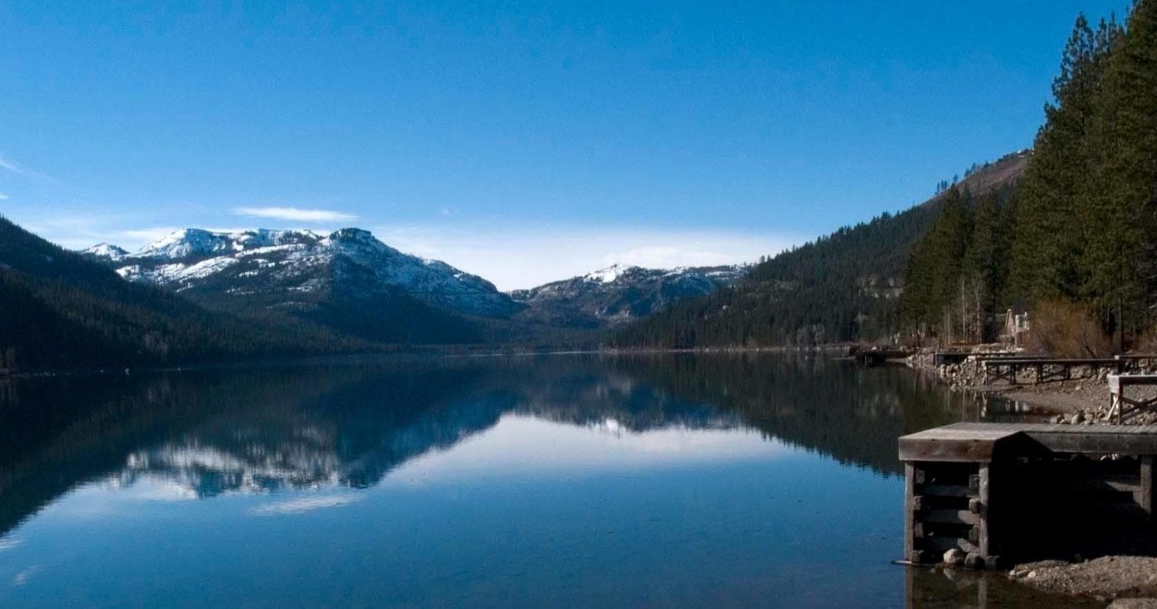 Mountain lake sunrise reflection with dock and pine forest