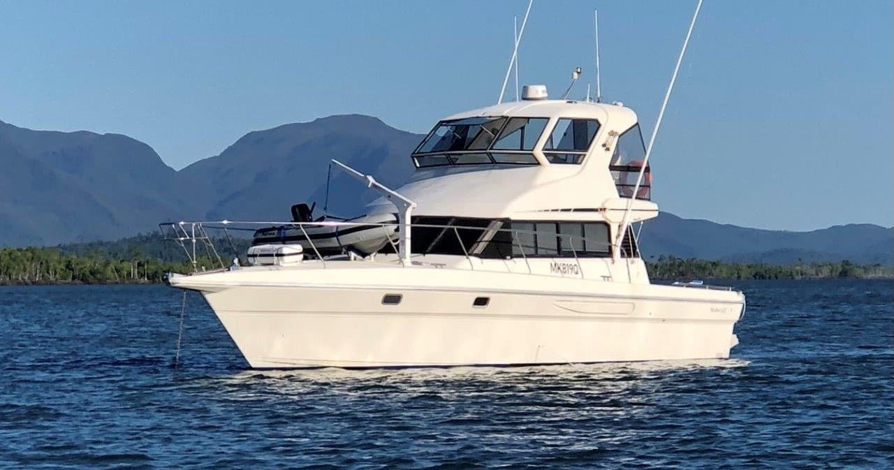 Motor yacht cruising coastal waters with mountain backdrop