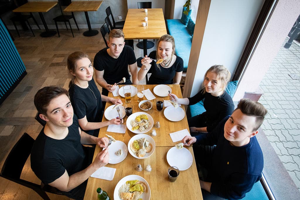 Friends sharing pierogi plates at wooden table inside restaurant