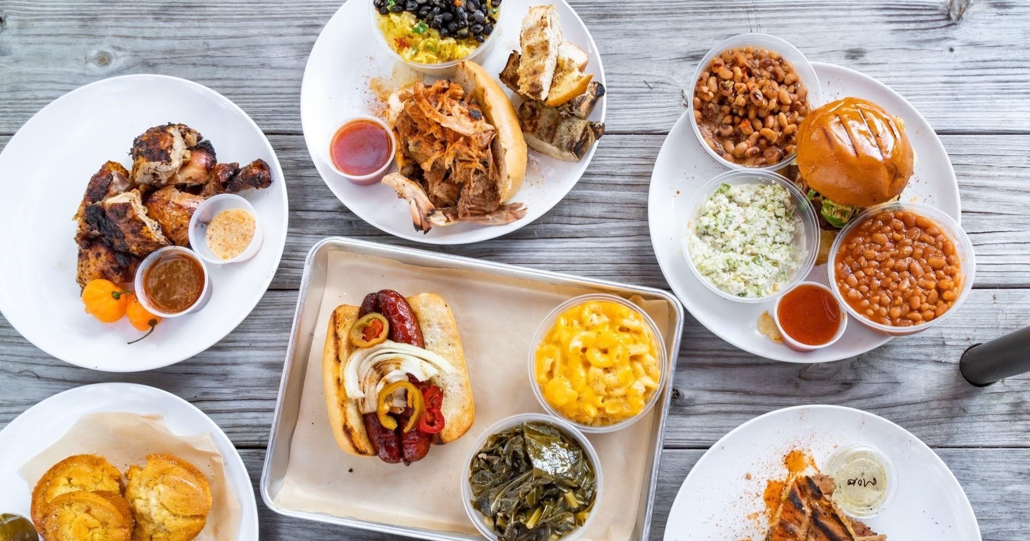 BBQ plates and sides on rustic wooden table for outdoor meal
