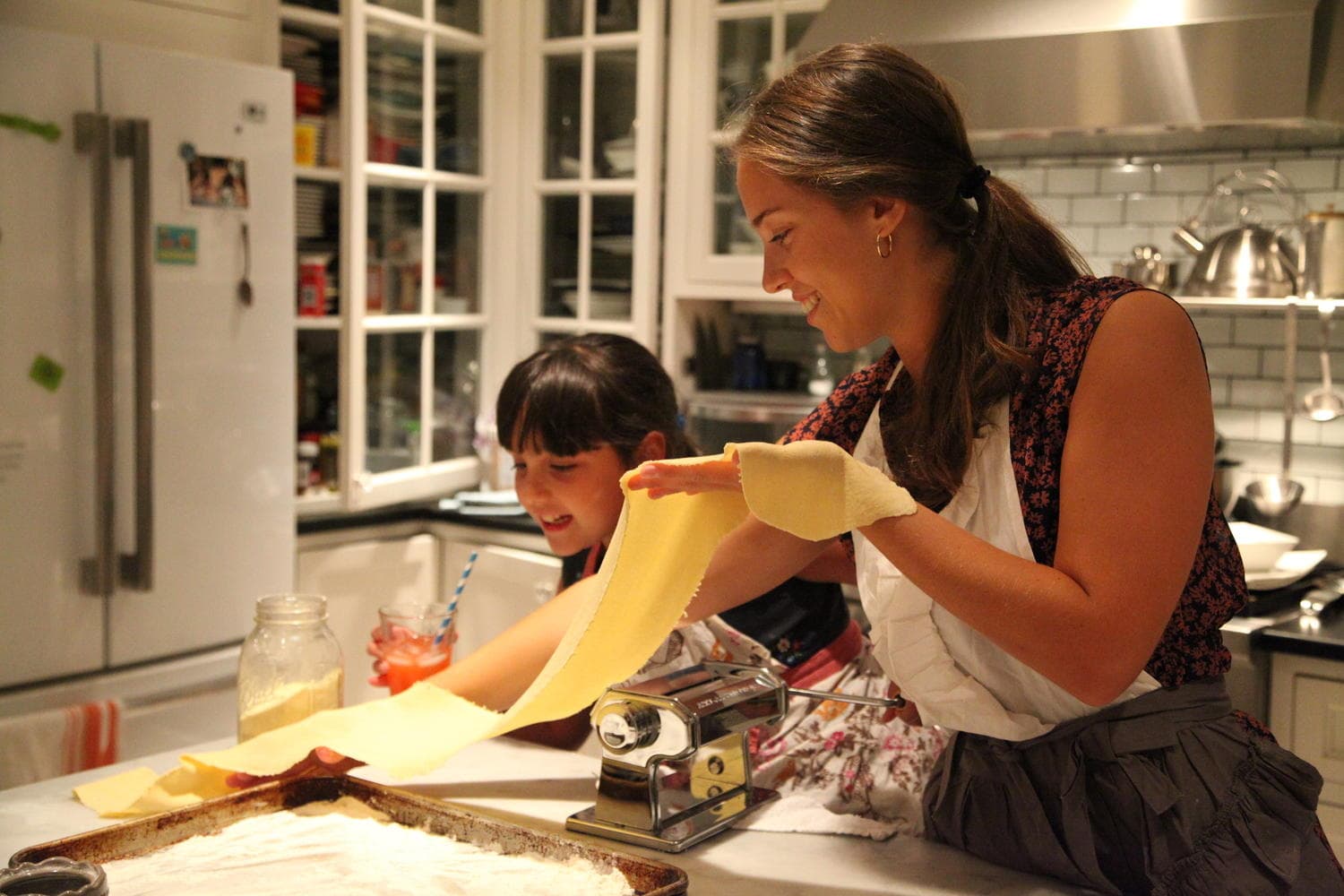 Mother and child rolling fresh pasta in a home kitchen