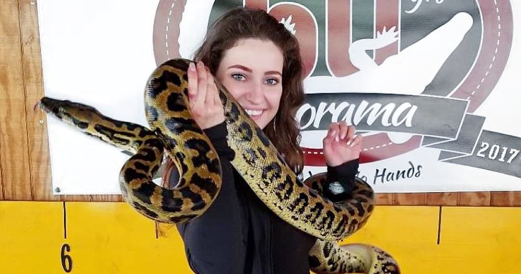 Visitor posing with large yellow Python inside Gatorama exhibit area