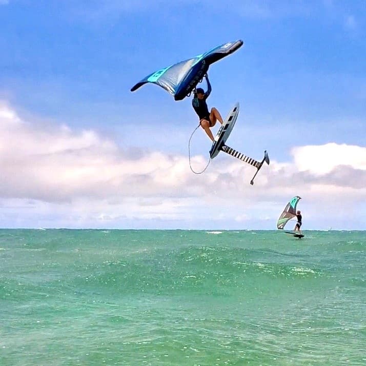 Wing foiler launching high above turquoise Maui ocean waves