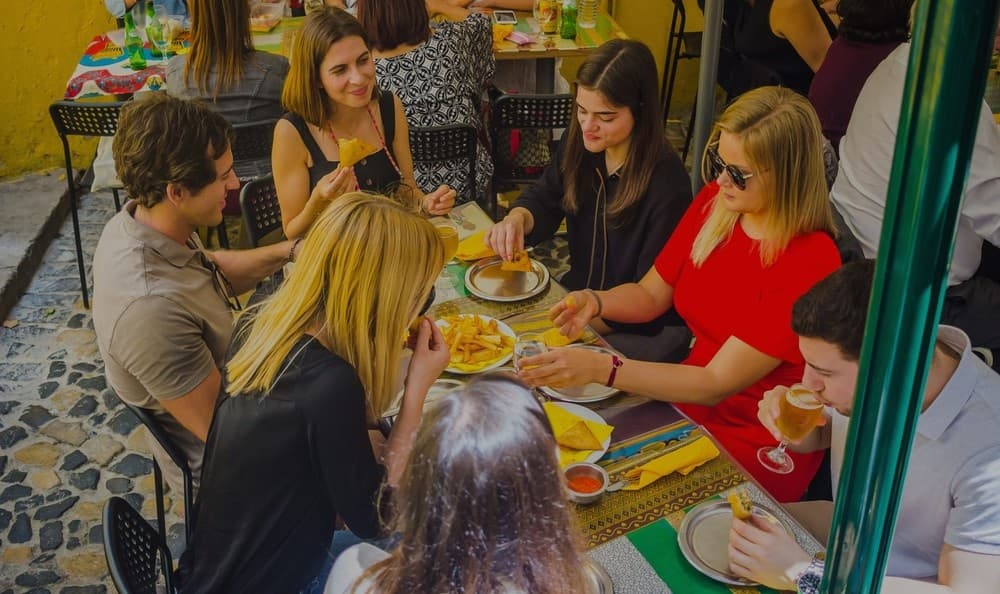Group dining outdoors at Lisbon street cafe on cobblestone