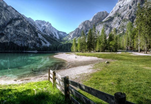 Alpine lake shoreline with meadow and mountain peaks for hiking
