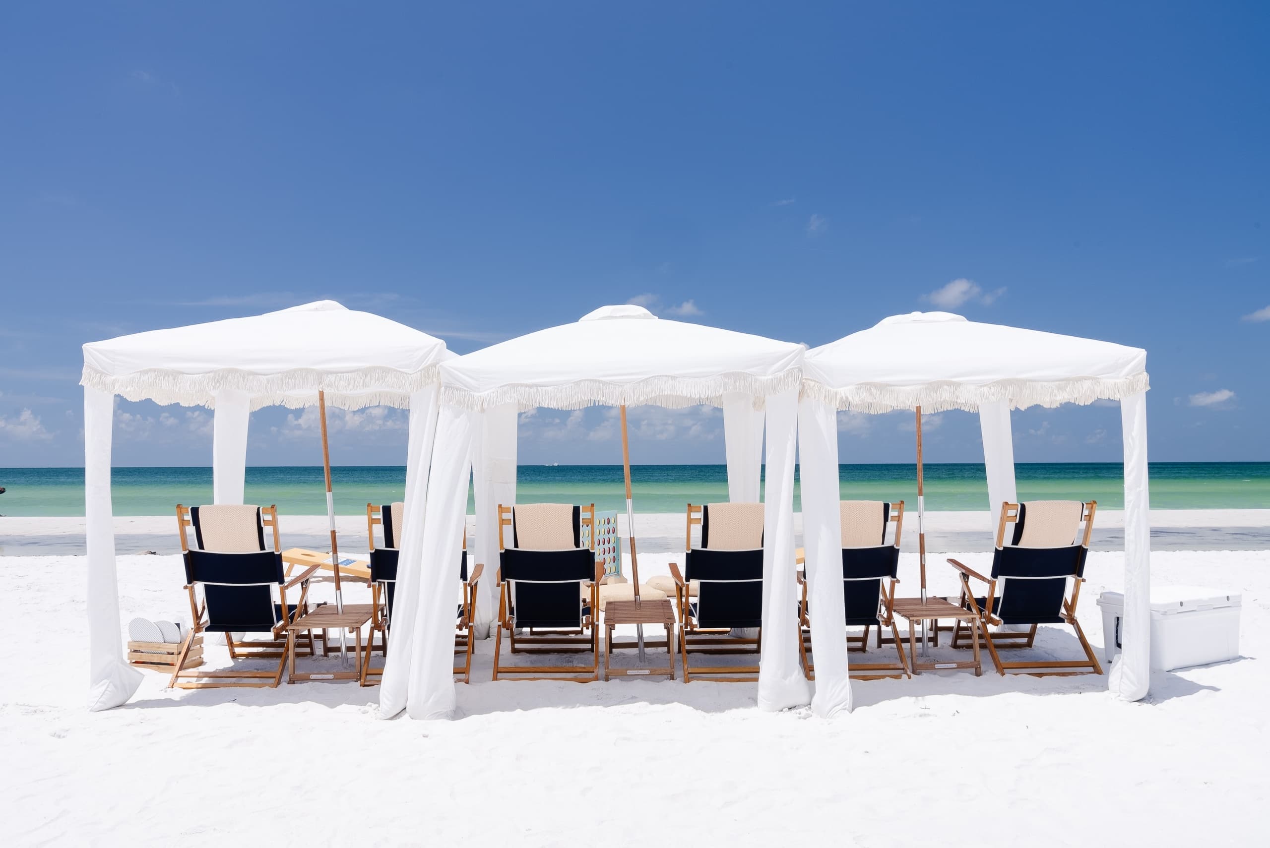 Shaded beach cabanas with reclining chairs by calm ocean horizon