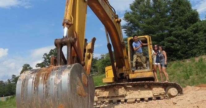 Excavator ride on rural site with operator and guests