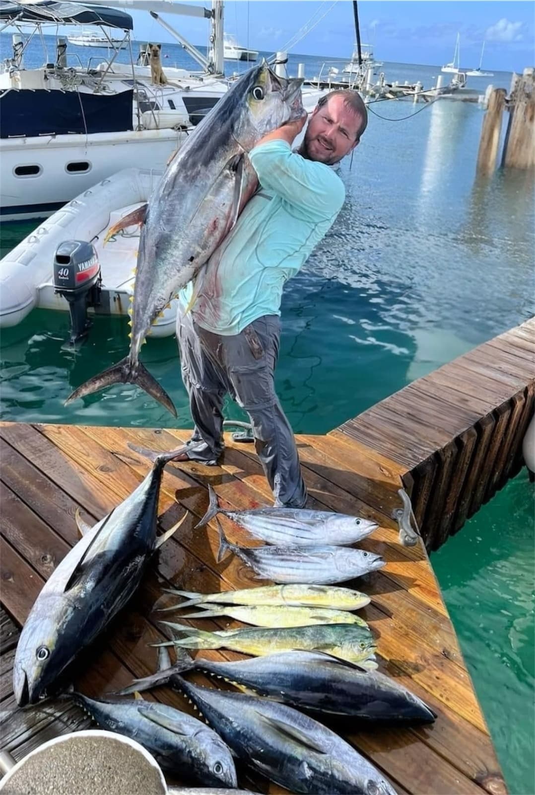 Angler posing with multiple freshly caught tuna and mahi on dock