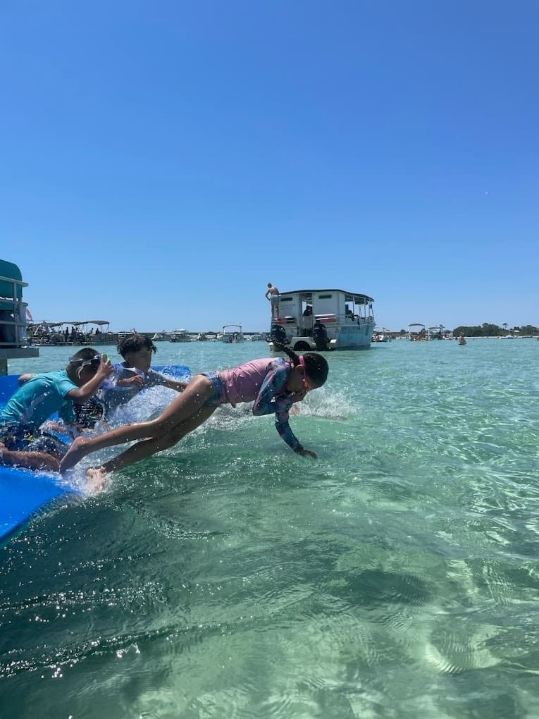 Kids jumping from pontoon into clear shallow Gulf waters