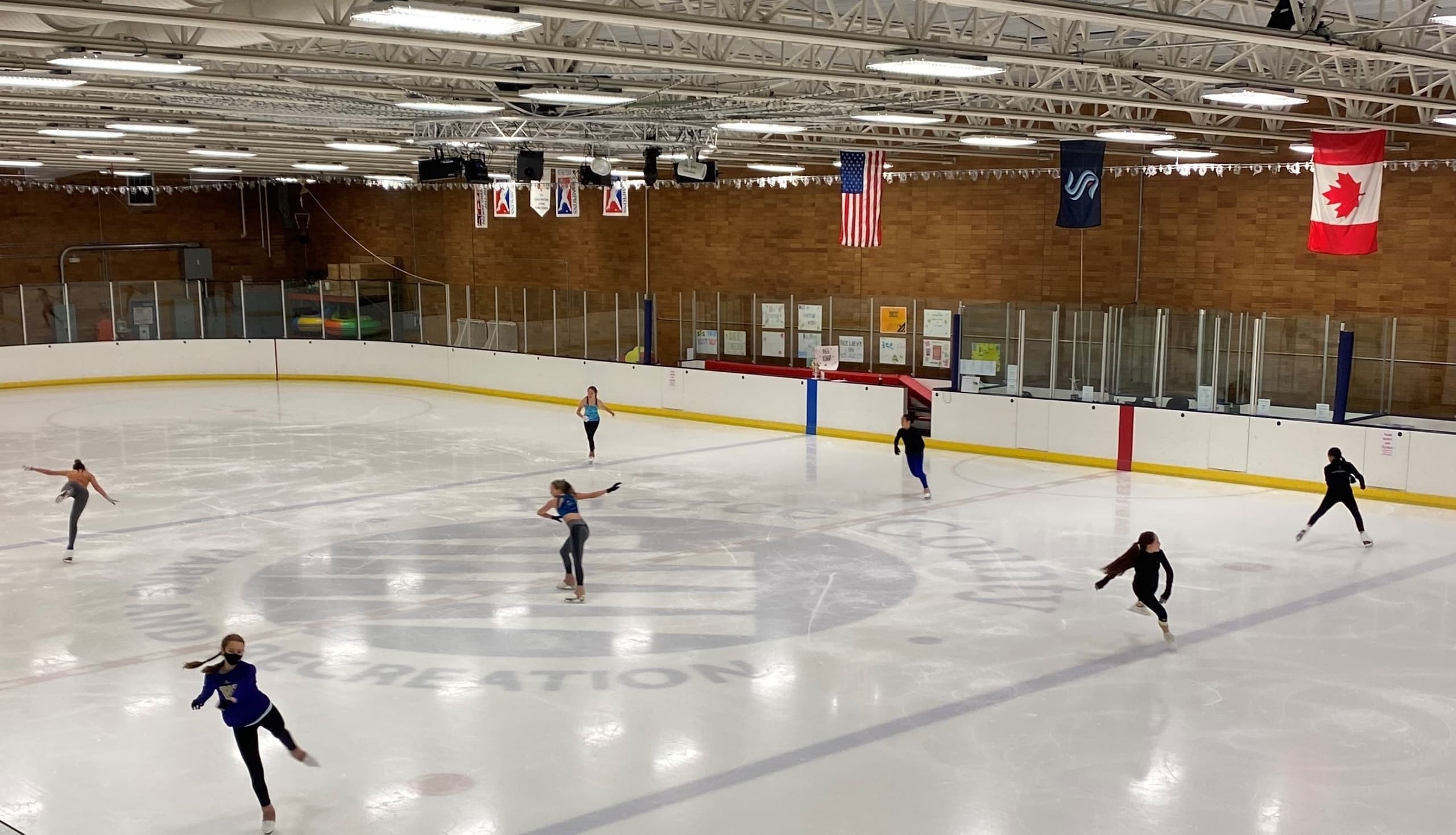 Figure skaters practicing on indoor ice rink at community arena