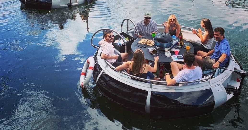 Friends socializing on round boat cruising quiet Lake Austin bay