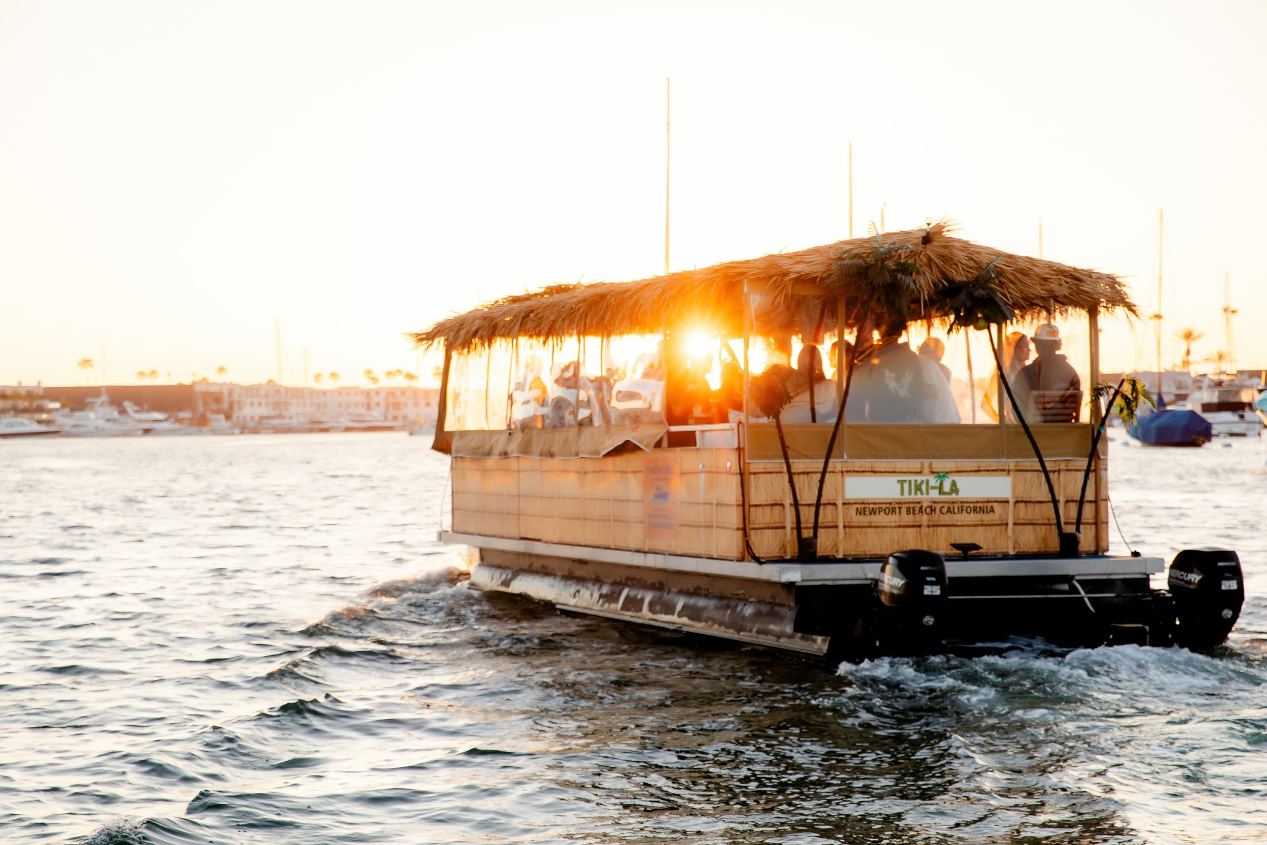 Tiki-style sunset cruise boat sailing on shimmering harbor waters