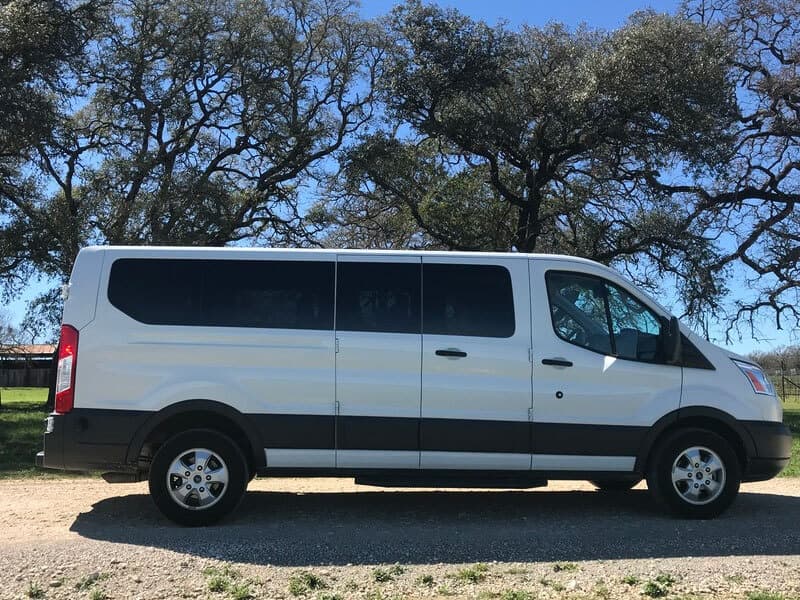 Shuttle van parked under oaks at vineyard for wine tour transport