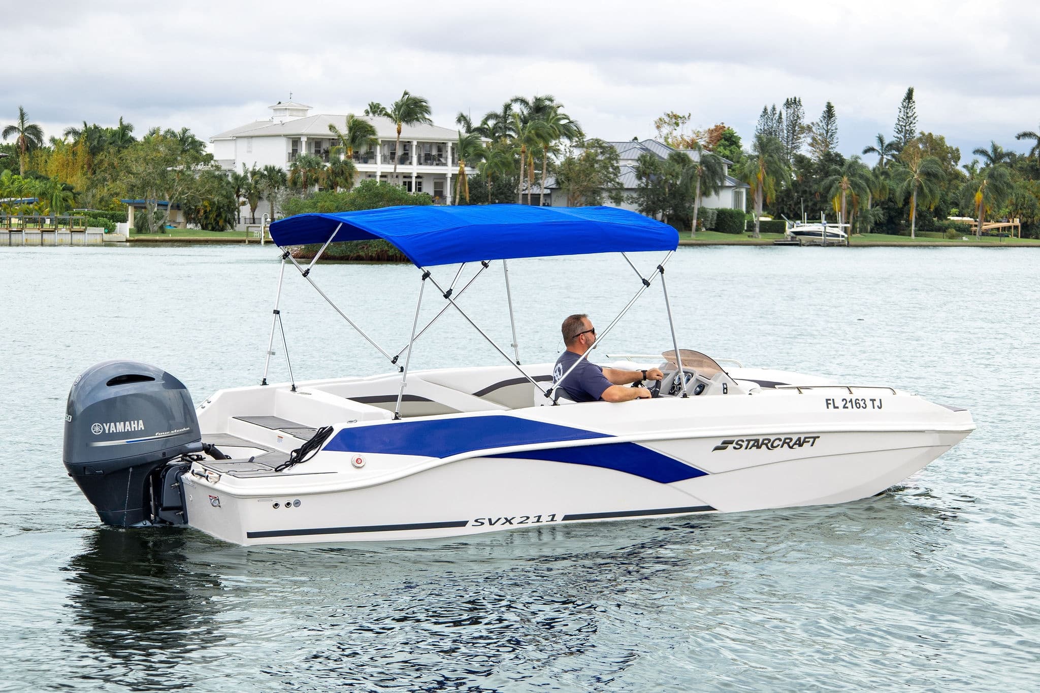White speedboat with blue canopy anchored in scenic residential bay