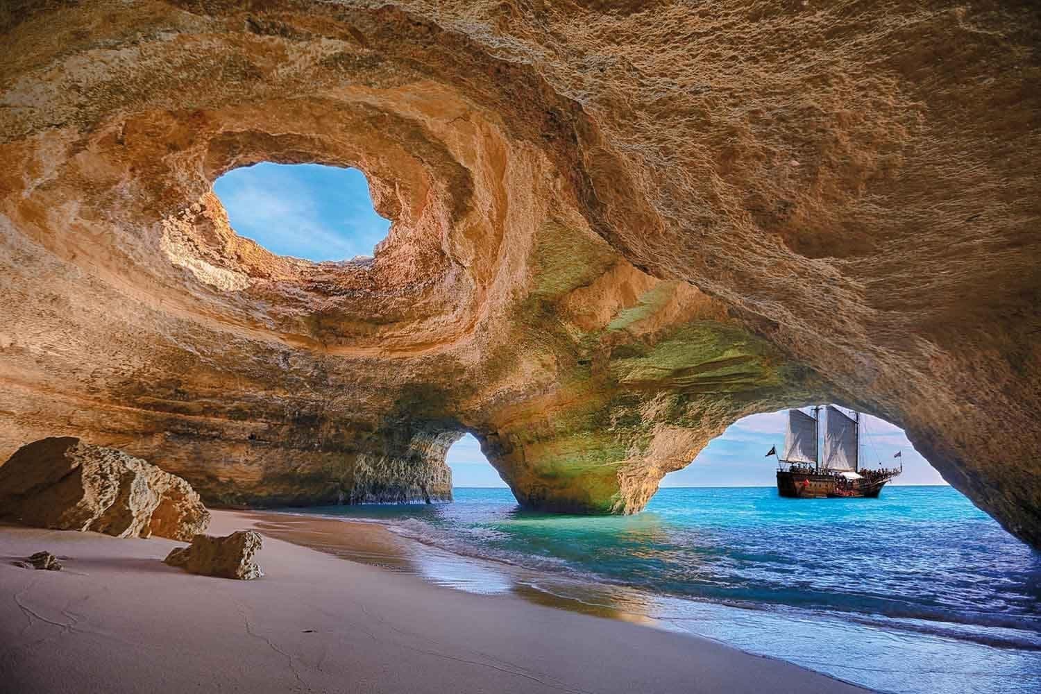 Sea cave with boat entering Benagil archway and turquoise waters