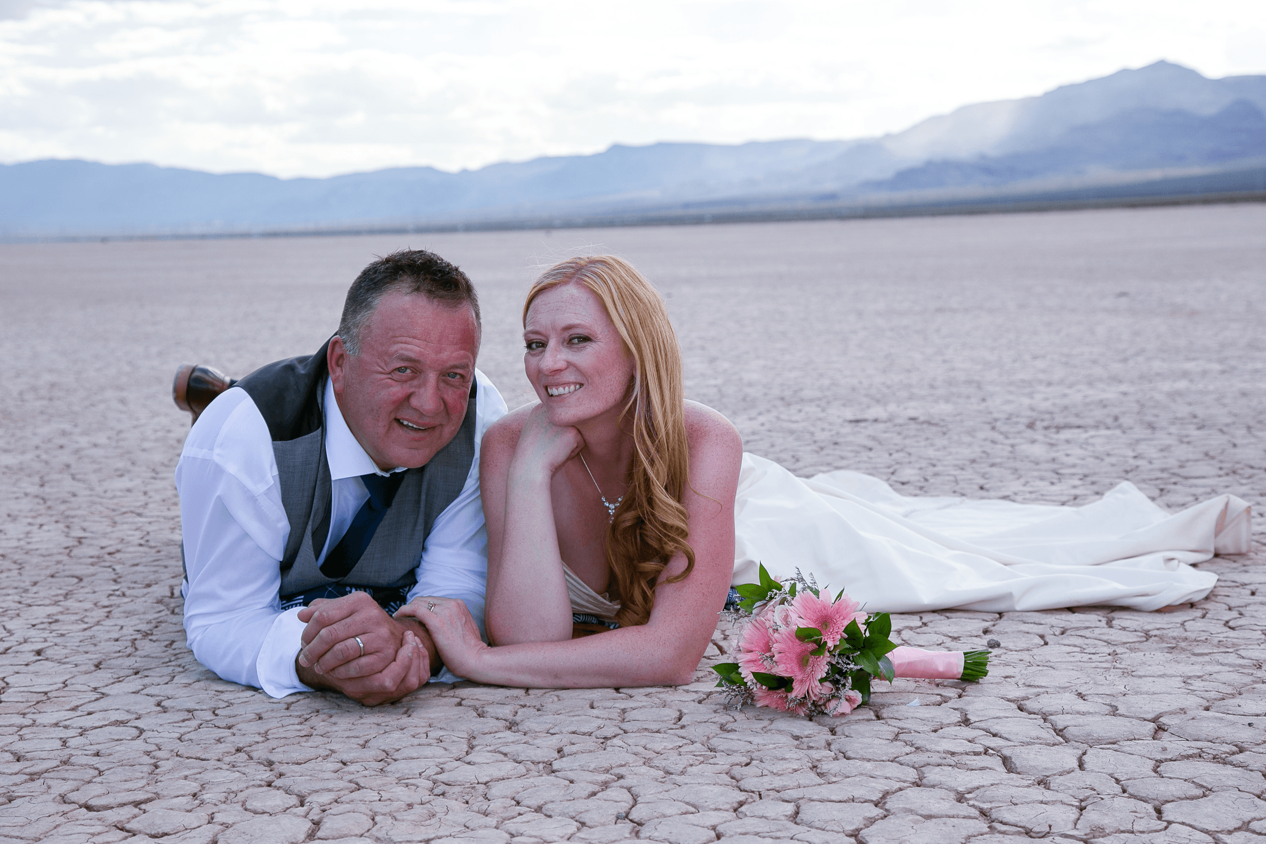Newlyweds reclining on dry lake bed desert near Las Vegas
