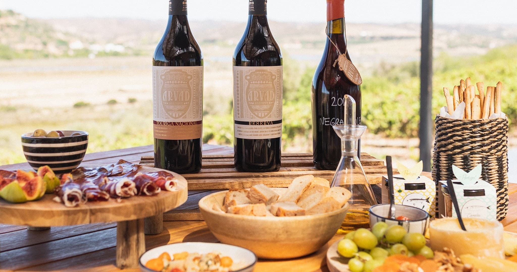Outdoor tasting table with wine bottles, bread, and olives