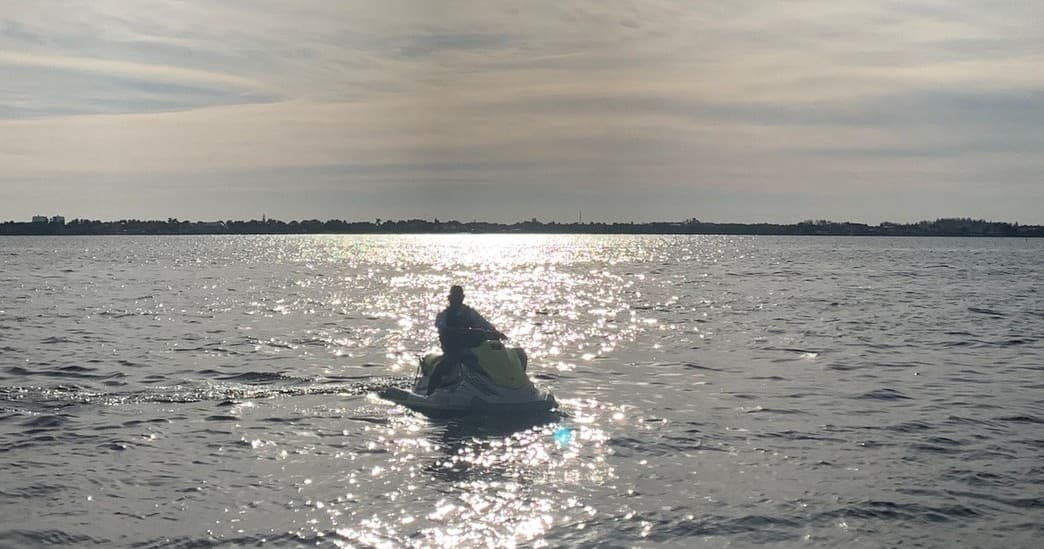 Jet ski silhouette paddling at sunrise on tranquil bay