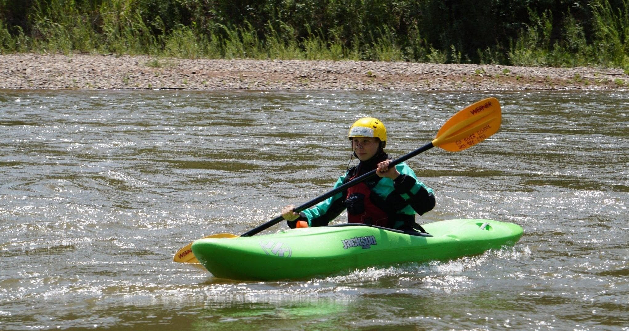 Solo kayaker paddling a calm river through green riparian banks