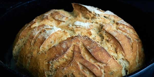 Artisan sourdough loaf baking in cast-iron Dutch oven, rustic kitchen