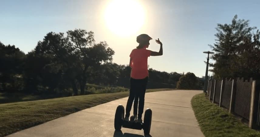 Person riding a Segway along a sunlit Houston park trail