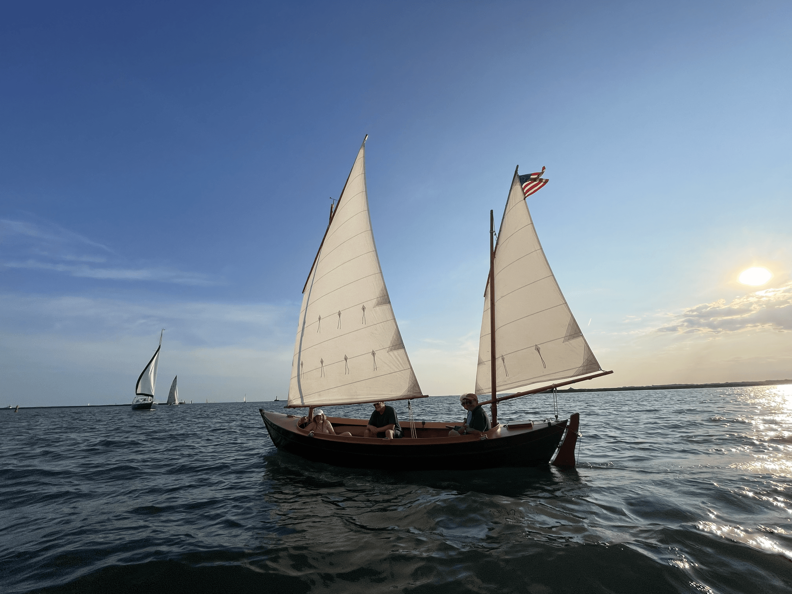 Classic sailboat cruising on open lake at sunset, scenic sailing