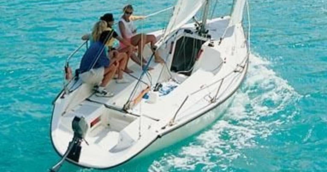 Group aboard sailboat trimming sails in bright coastal waters
