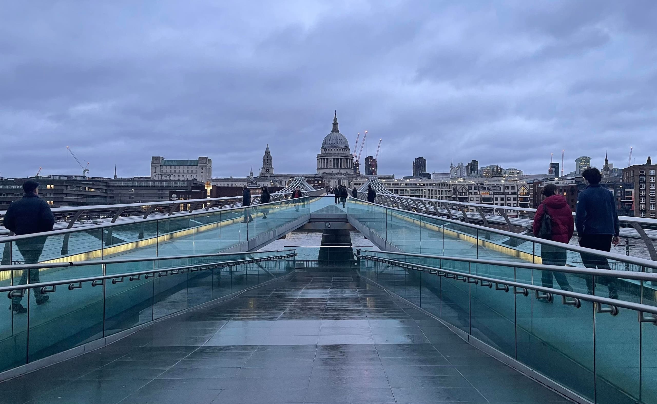 Pedestrians crossing Millennium Bridge toward St Paul's Cathedral London