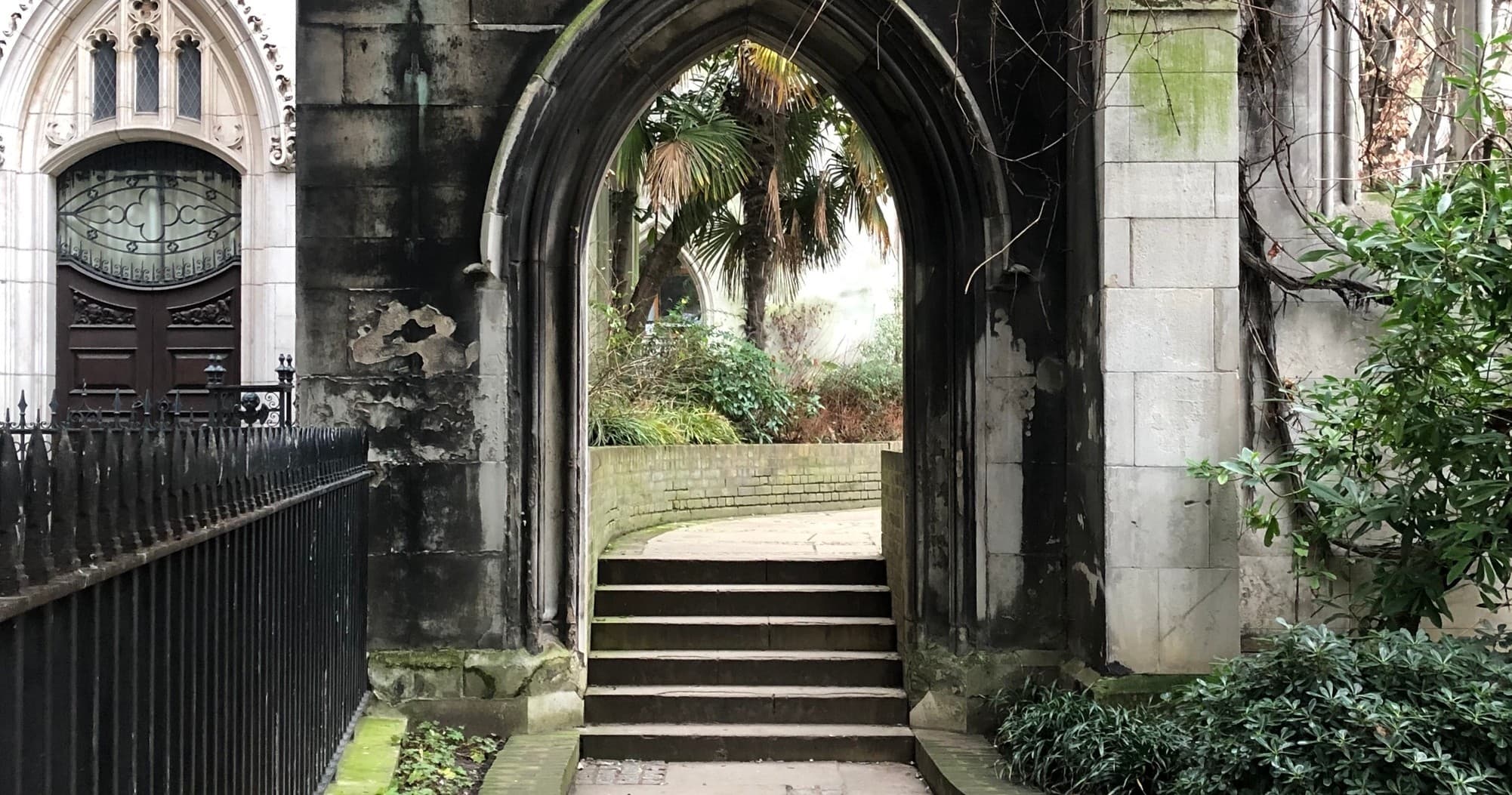 Stone archway and garden steps leading to tranquil courtyard, London