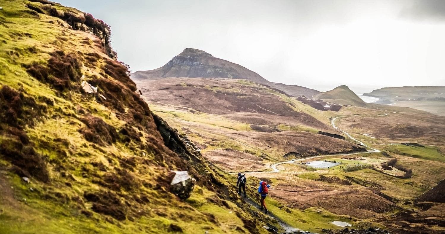Hikers traversing rugged Highland trail across sweeping ridges